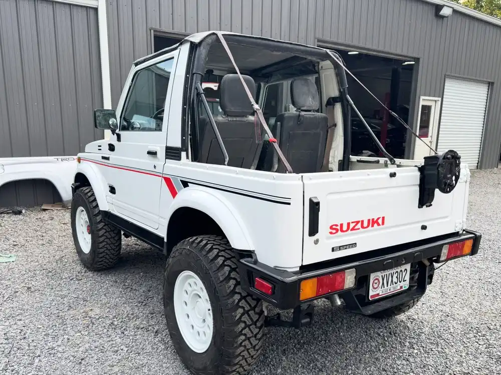 Rear of the restored white Suzuki Samurai with its spare tire